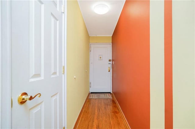 corridor with light wood-type flooring and baseboards