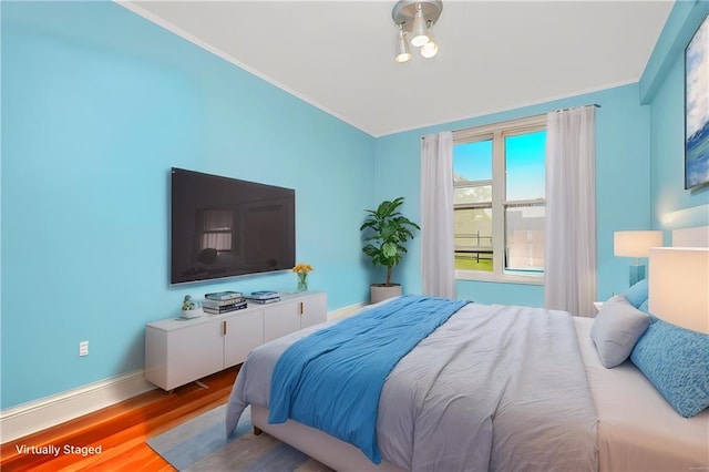 bedroom with crown molding, wood finished floors, and baseboards