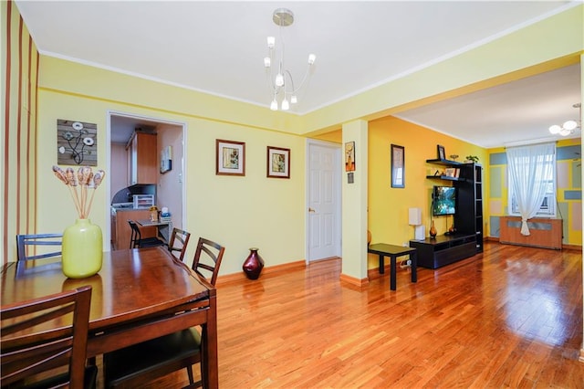 dining room featuring light wood-style floors, a chandelier, crown molding, and baseboards