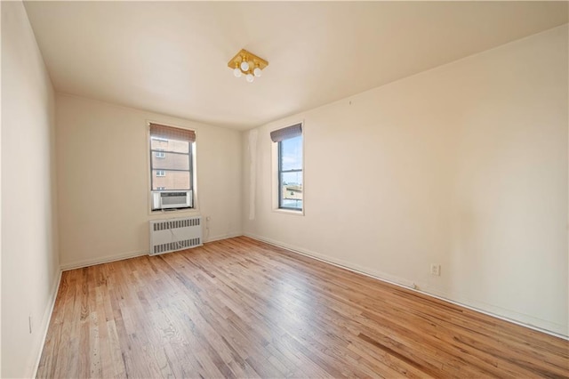 empty room with cooling unit, baseboards, radiator, and wood finished floors