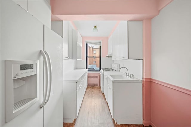 washroom with washer / dryer, radiator heating unit, light wood finished floors, and a sink