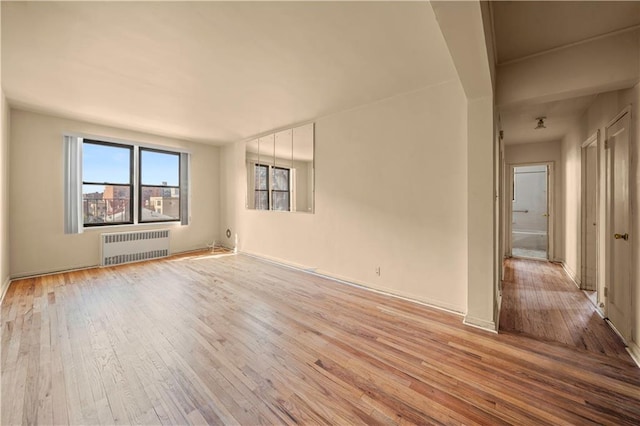 unfurnished room with light wood-style floors and radiator heating unit