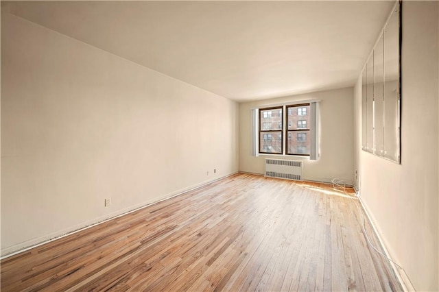 spare room featuring radiator heating unit and light wood finished floors