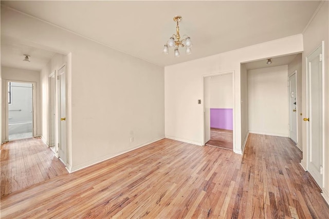 unfurnished room featuring light wood-type flooring, baseboards, and a chandelier