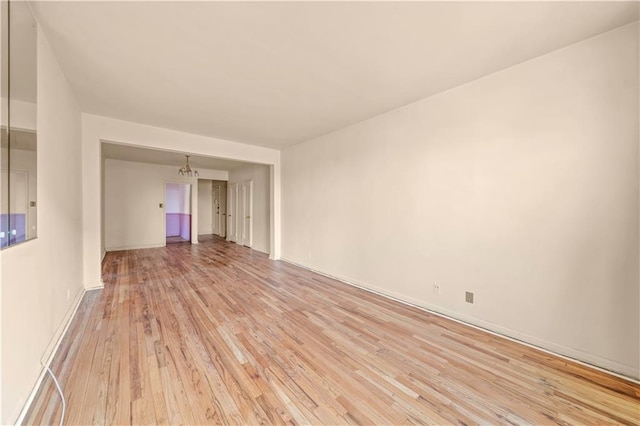 empty room featuring a chandelier and light wood finished floors