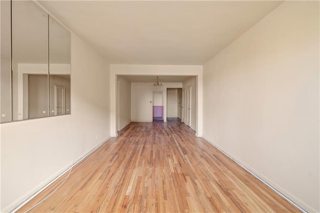 spare room featuring a notable chandelier and wood finished floors