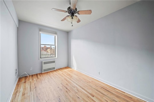 spare room featuring radiator, ceiling fan, and wood finished floors