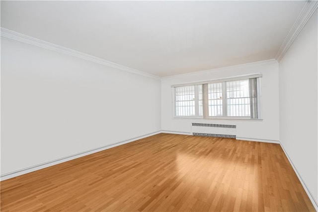 spare room with light wood-style flooring, radiator heating unit, crown molding, and baseboards