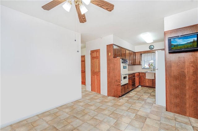 2121 Kimball St, Brooklyn, NY 11234 - kitchen featuring ceiling fan, white appliances, stone finish floors, brown cabinets, and light countertops