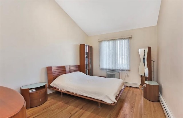 bedroom featuring wood finished floors, baseboard heating, a baseboard heating unit, a wall unit AC, and vaulted ceiling
