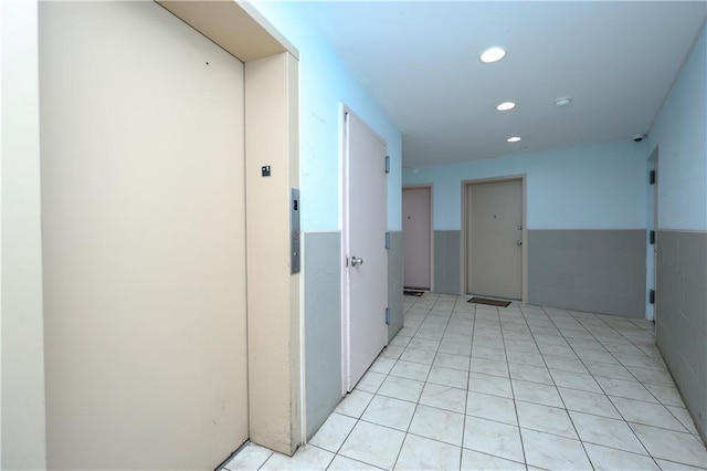8895 26th Ave Unit 4A, Brooklyn, NY 11214 - corridor with elevator, recessed lighting, light tile patterned floors, and a wainscoted wall