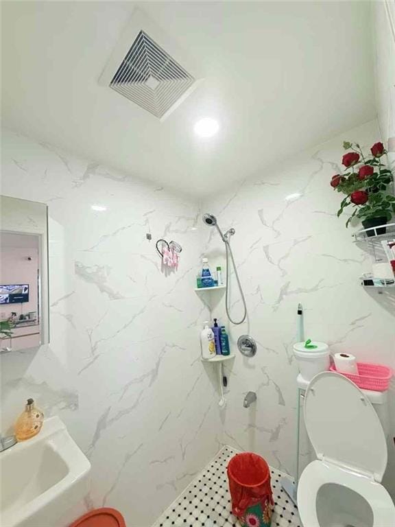 full bath with a marble finish shower, toilet, and visible vents