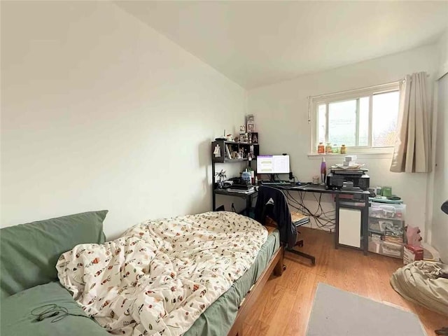 bedroom with vaulted ceiling and wood finished floors