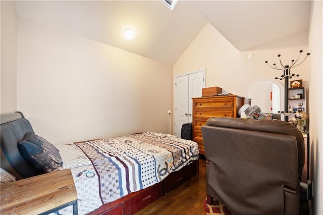 bedroom with a closet, dark wood-style flooring, vaulted ceiling, and visible vents
