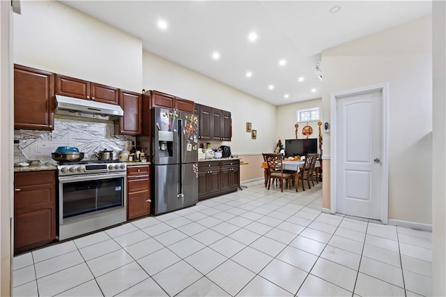 kitchen with fridge with ice dispenser, under cabinet range hood, decorative backsplash, light tile patterned flooring, and stainless steel stove
