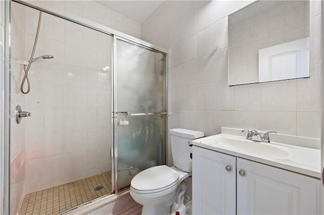 full bathroom featuring tile walls, a shower stall, toilet, and vanity