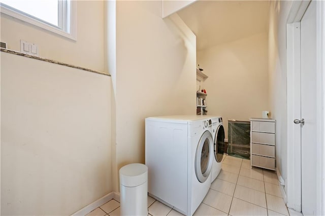 washroom with light tile patterned flooring, washer and clothes dryer, laundry area, and baseboards