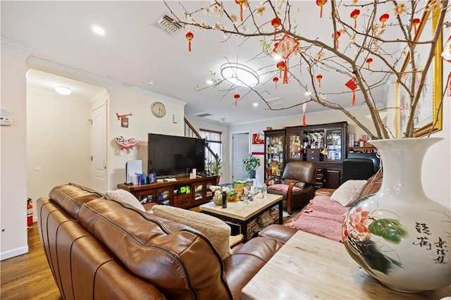 living area featuring visible vents, baseboards, recessed lighting, ornamental molding, and wood finished floors