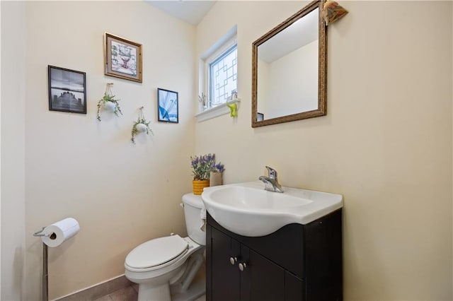 half bath with toilet, vanity, and baseboards