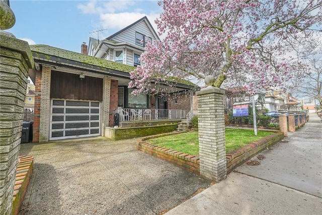 view of front of property featuring an attached garage, a porch, concrete driveway, and brick siding