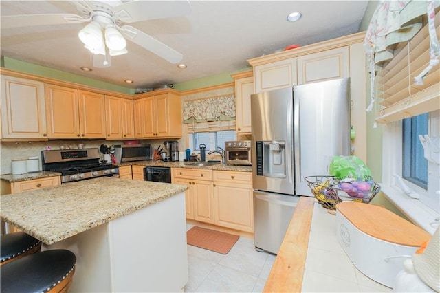 kitchen featuring stainless steel appliances, a sink, a breakfast bar, a kitchen island, and light stone countertops