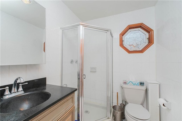 bathroom with tile walls, a shower stall, vanity, and toilet