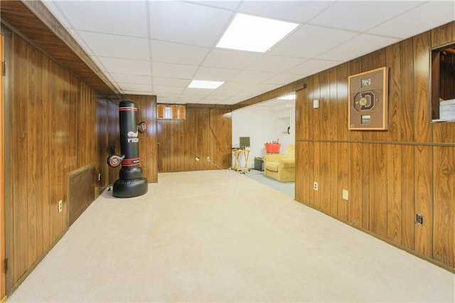finished basement featuring wood walls, carpet, and a drop ceiling