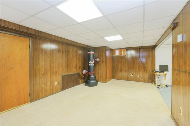 finished basement with wood walls, carpet floors, and a paneled ceiling