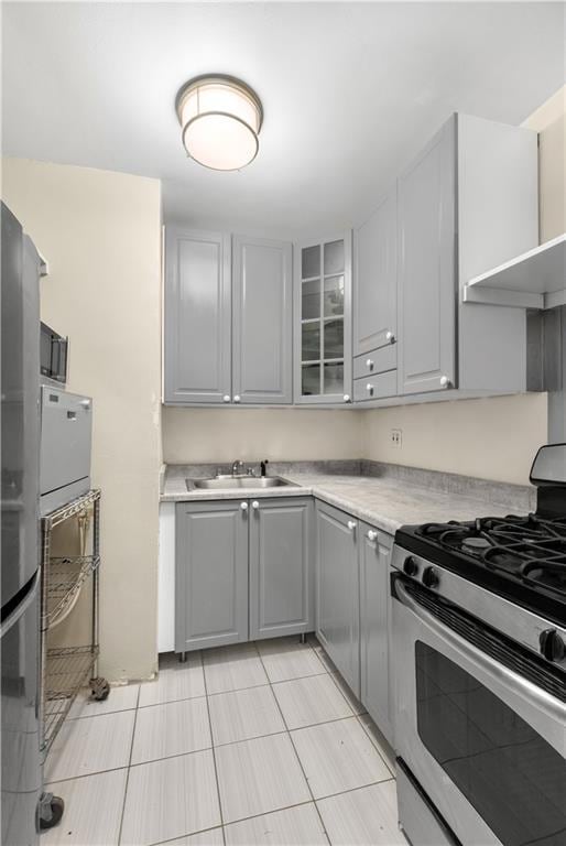 kitchen featuring a sink, gray cabinetry, gas stove, light countertops, and light tile patterned floors