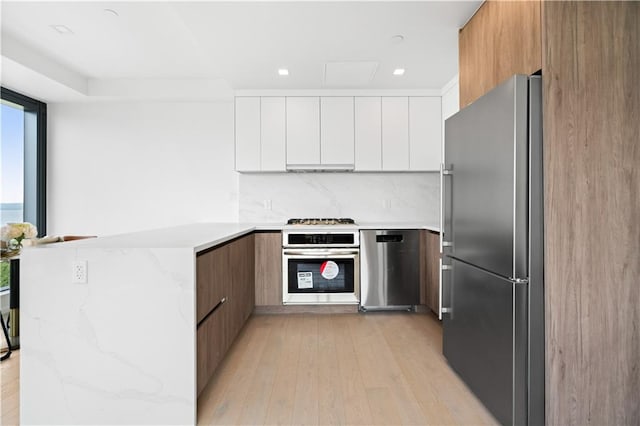2286 Cropsey Ave Unit 5F, Brooklyn, NY 11214 - kitchen featuring a peninsula, light wood-style floors, modern cabinets, white cabinets, and stainless steel appliances