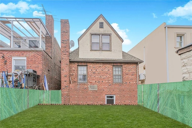 back of property featuring a yard, brick siding, a shingled roof, and a fenced backyard