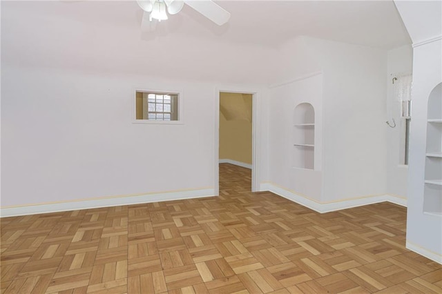 unfurnished room with baseboards, built in features, and ceiling fan