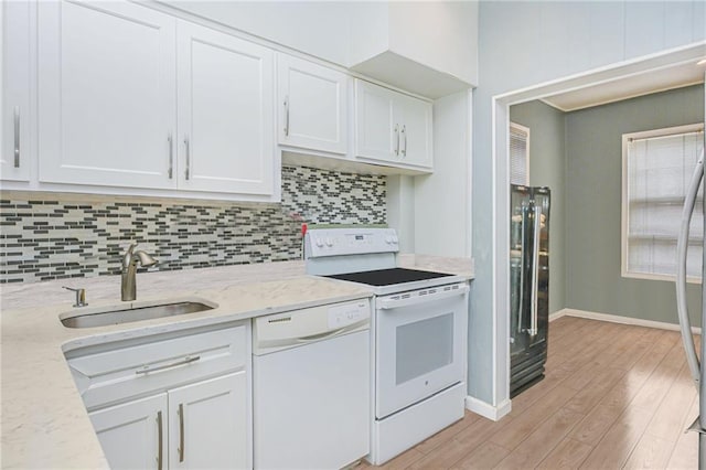 kitchen featuring a sink, decorative backsplash, white cabinets, and white appliances