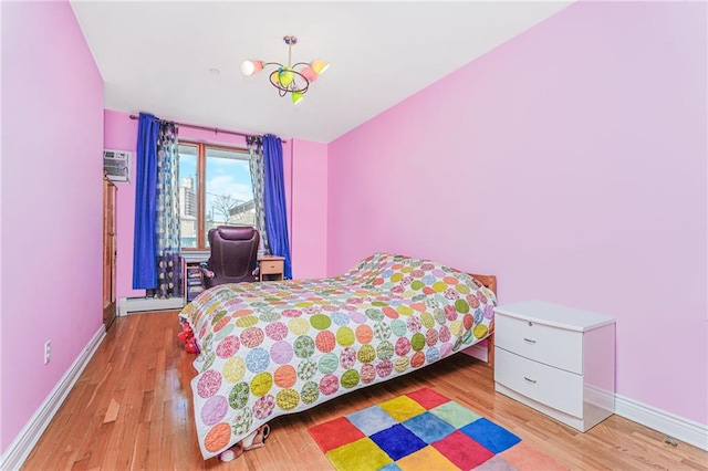 197 Bay 47th St Unit 5, Brooklyn, NY 11214 - bedroom with light wood-style floors, baseboards, an AC wall unit, and a baseboard radiator