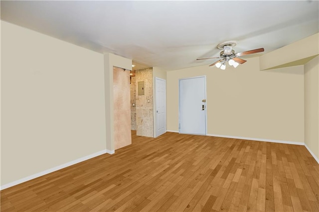 spare room featuring baseboards, light wood-type flooring, and a ceiling fan