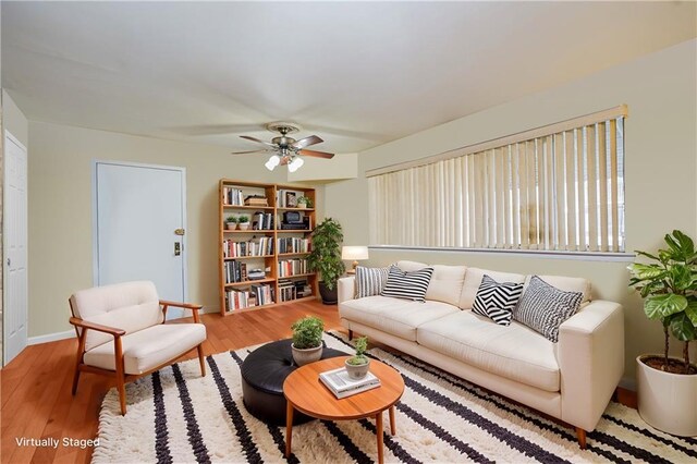 living area featuring a ceiling fan, baseboards, and wood finished floors
