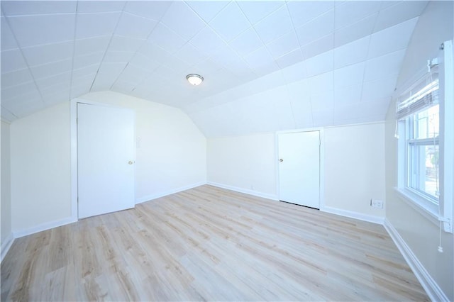 additional living space with baseboards, light wood-type flooring, and lofted ceiling