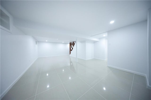 finished below grade area with tile patterned floors, recessed lighting, stairway, and baseboards