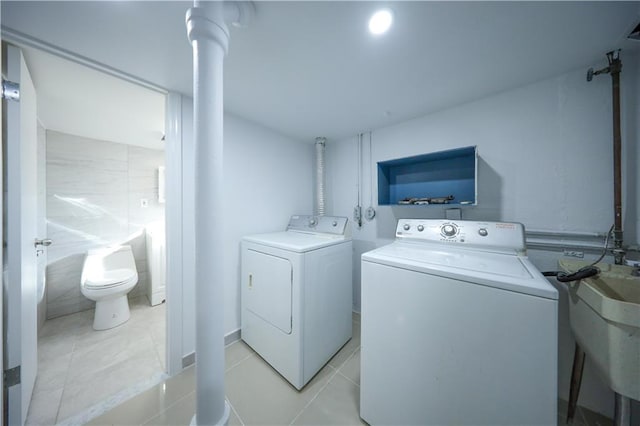 laundry area featuring a sink, light tile patterned floors, and independent washer and dryer