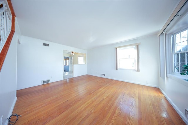 unfurnished living room featuring wood finished floors, ceiling fan, baseboards, and visible vents
