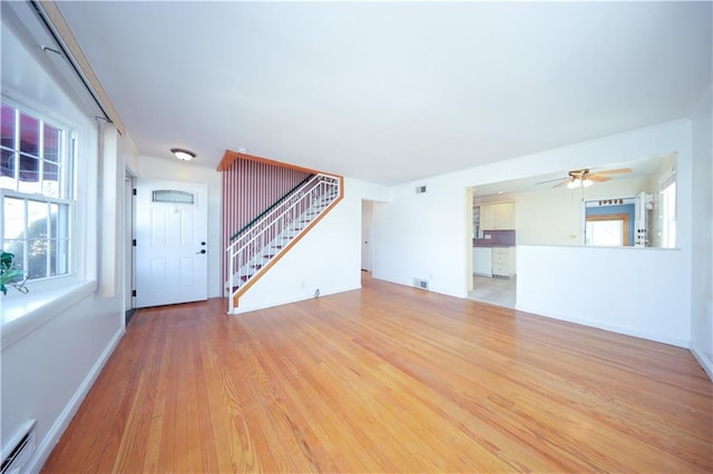 unfurnished living room with baseboards, stairway, visible vents, ceiling fan, and wood finished floors