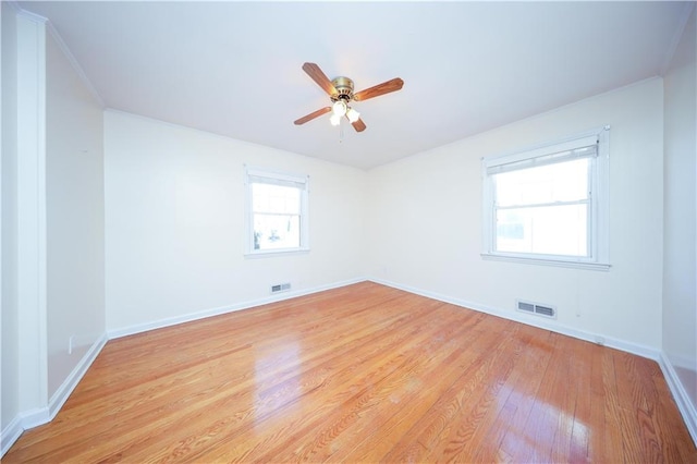 empty room featuring light wood-style flooring, baseboards, a ceiling fan, and visible vents