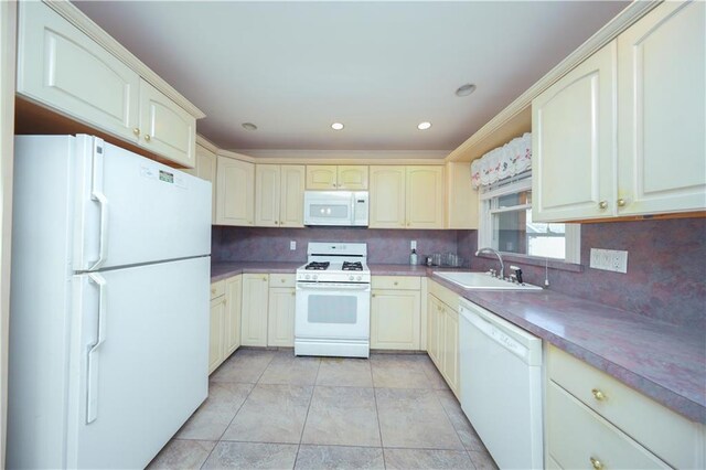 kitchen with recessed lighting, white appliances, cream cabinets, decorative backsplash, and a sink