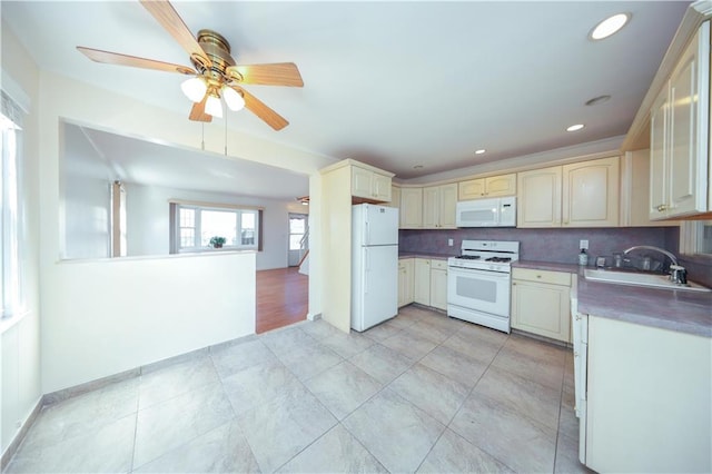 kitchen featuring tasteful backsplash, cream cabinets, a sink, and white appliances