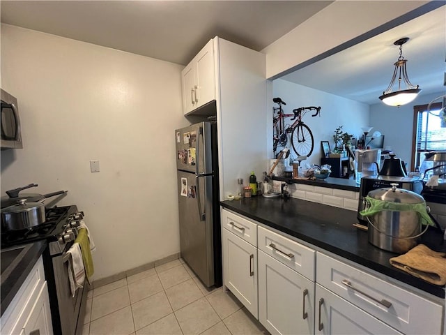 385 Douglass St Unit 3B, Brooklyn, NY 11217 - kitchen with appliances with stainless steel finishes, dark countertops, light tile patterned floors, white cabinets, and pendant lighting