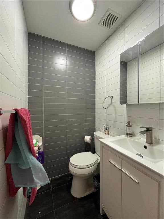 bathroom featuring toilet, tile patterned flooring, tile walls, and visible vents