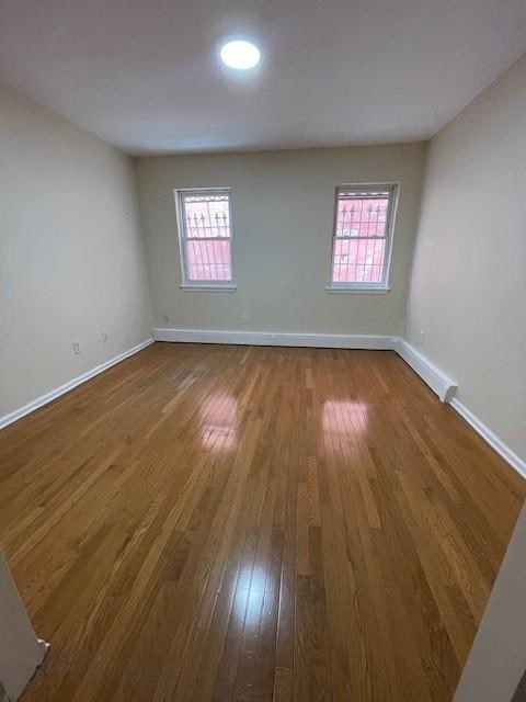 spare room featuring healthy amount of natural light, baseboards, and dark wood-type flooring