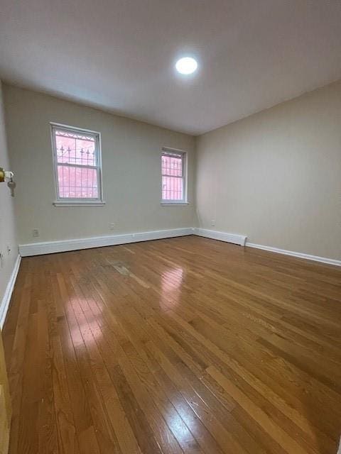 empty room with hardwood / wood-style flooring and baseboards