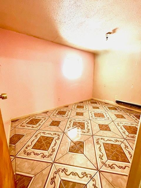 tiled empty room with a textured ceiling