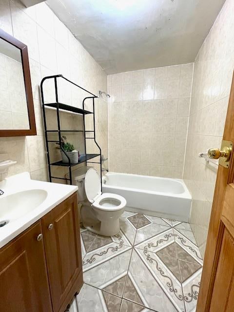 bathroom featuring tile walls, toilet,  shower combination, tile patterned floors, and vanity